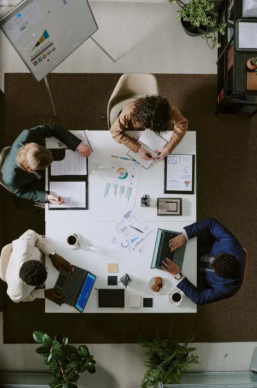 WordPress website development team meeting from above, reviewing strategy charts, wireframes, and analytics reports during project planning phase